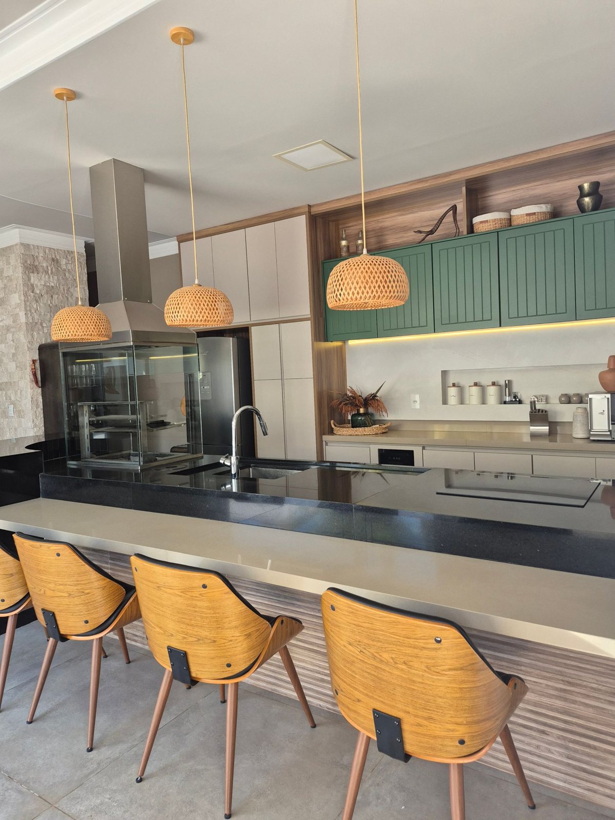 Cozinha gourmet planejada com armários verdes, nicho amadeirado e ilha em granito