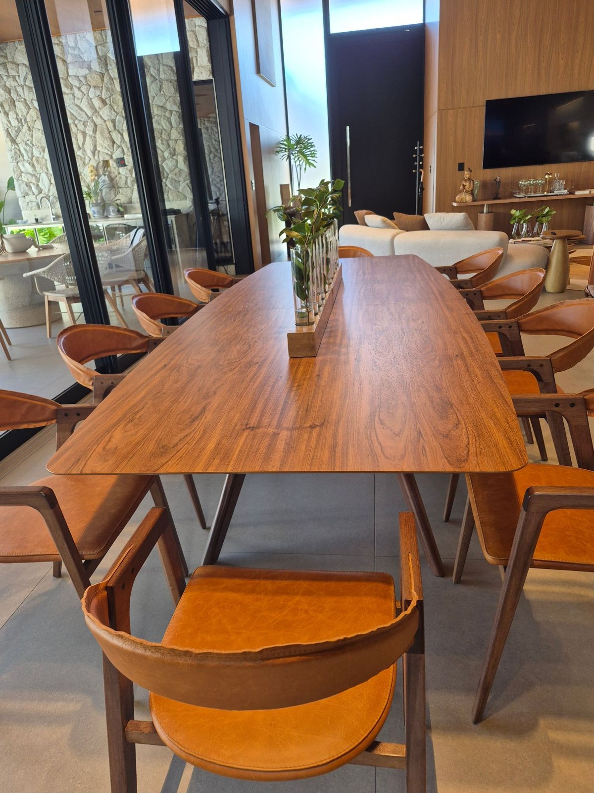 Sala de jantar integrada ao living com painel amadeirado, mesa de madeira e cadeiras de couro